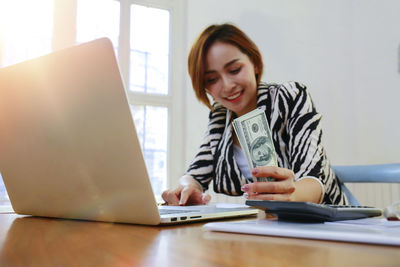 Young woman using phone while sitting on table