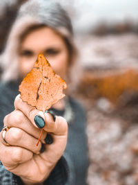 Close-up of woman holding autumn leaf