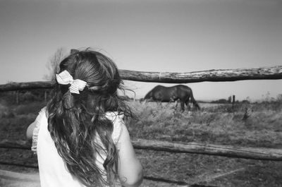 Rear view of girl standing by railing against sky