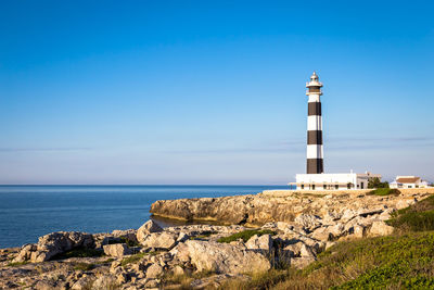 Lighthouse by sea against sky