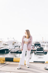 Portrait of a happy cheerful emotional traveling girl in fashionable clothes near yachts and water
