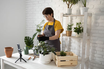 Side view of woman holding christmas tree at home