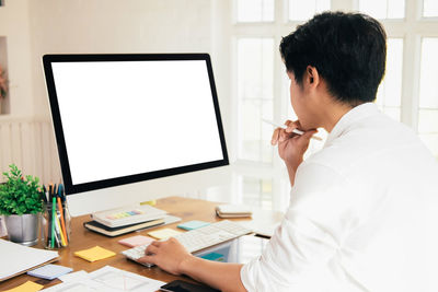 Side view of businessman using computer at desk in office