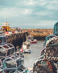 Boats moored at harbor against sky