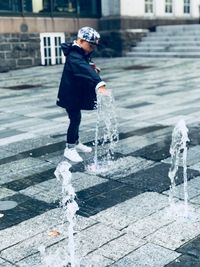 Full length of boy standing by fountain