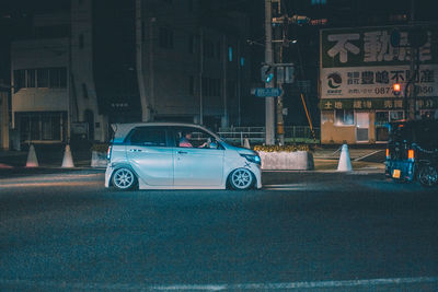 Car on street against buildings at night