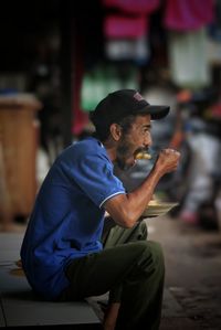 Side view of young man looking away while sitting outdoors