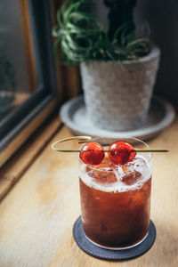 Close-up of cocktail with cherries served on wooden table