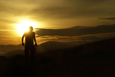 Silhouette man standing on street against sky during sunset