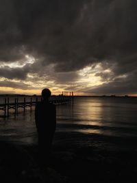 Silhouette of pier on beach against sky during sunset