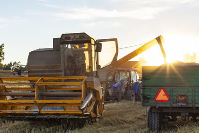 Combine harvester working in field at sunset