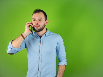 Portrait of young man standing against gray background