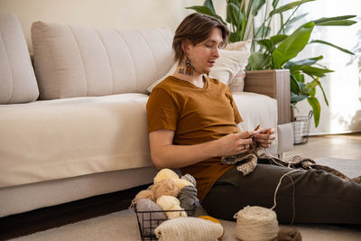 Young woman using laptop while sitting on sofa at home