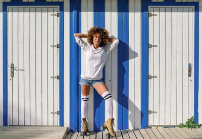 Portrait of woman with roller skates standing amidst white doors