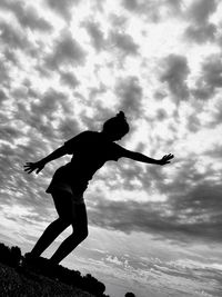 Low angle view of silhouette woman jumping against sky