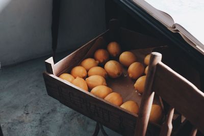 High angle view of lemons in wooden crate below table