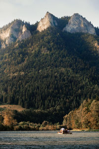 People on mountain by trees against mountains