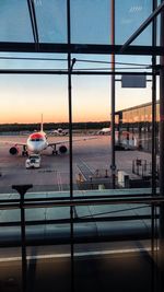 Airplane on airport runway against sky during sunset