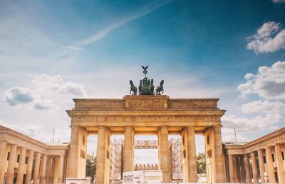 Statue in city against cloudy sky