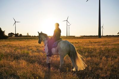 Woman riding horse on field against sky