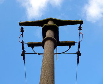 Low angle view of telephone pole against blue sky