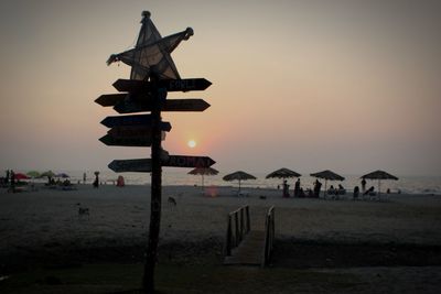 People on beach against sky during sunset