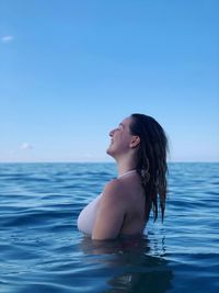 Young woman in swimming pool against sea