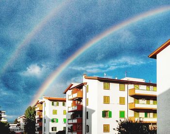 Rainbow over buildings in city against sky