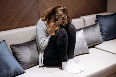 Young woman sitting on sofa at home