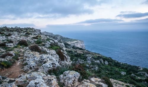 Scenic view of rocks by sea against sky