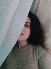 Portrait of beautiful woman amidst curtain