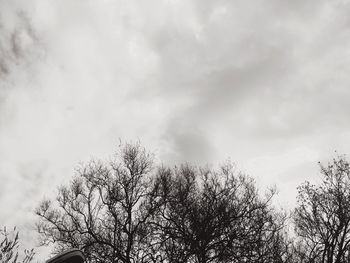 Low angle view of bare tree against cloudy sky