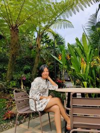 Side view of woman sitting on bench at park