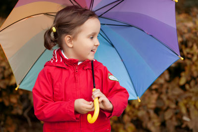 Cute girl holding umbrella while standing outdoors