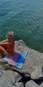 High angle view of woman sitting on rock at beach