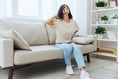 Young woman using mobile phone while sitting on sofa at home