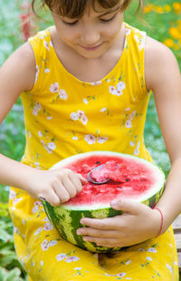 Midsection of woman holding yellow flower