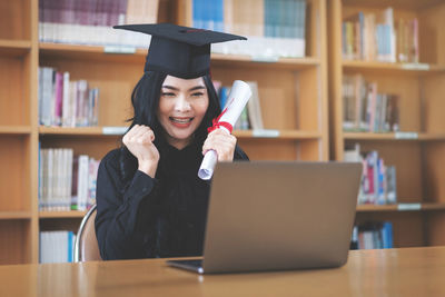 Portrait of smiling young woman using laptop on table