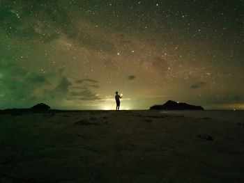Silhouette person standing on land against star field at night