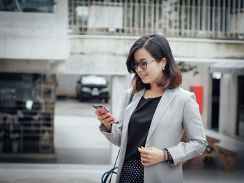 Young businesswoman using mobile phone in city