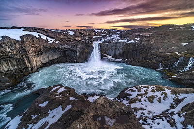 Scenic view of waterfall against sky during sunset
