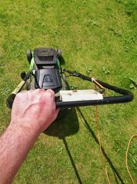 Cropped image of man using lawn mover on grassy field