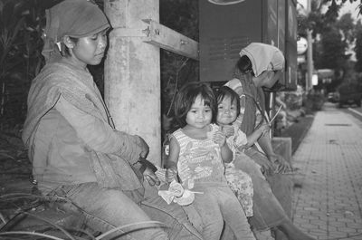 Women with daughters sitting on wall