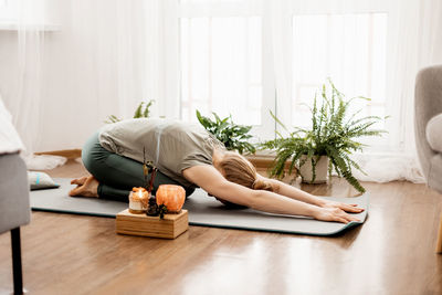 Beautiful young woman doing exercises and doing yoga at home