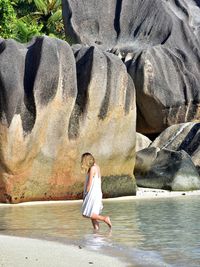 Side view of woman on beach against rock formation