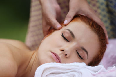 Massage therapist massaging young woman in yard