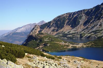Scenic view of lake and mountains against clear blue sky