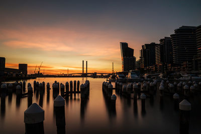 Panoramic view of wooden posts in sea against sky during sunset