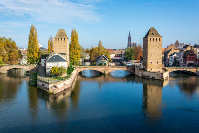 Bridge over river by buildings against sky