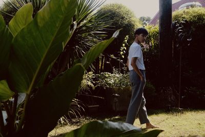 Boy standing by tree against plants